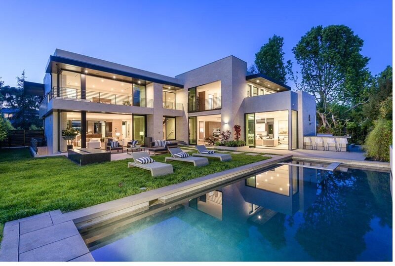 A modern glass home with a pool and gardens