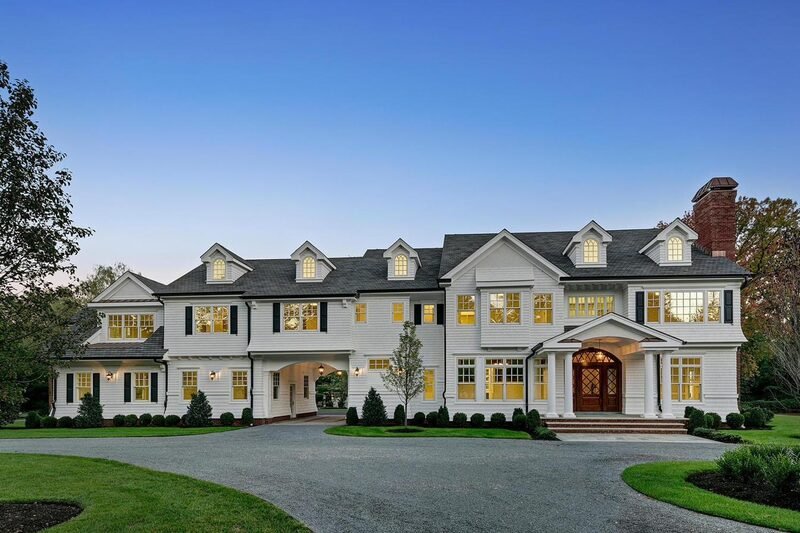 A white shingle colonial custom home at dusk